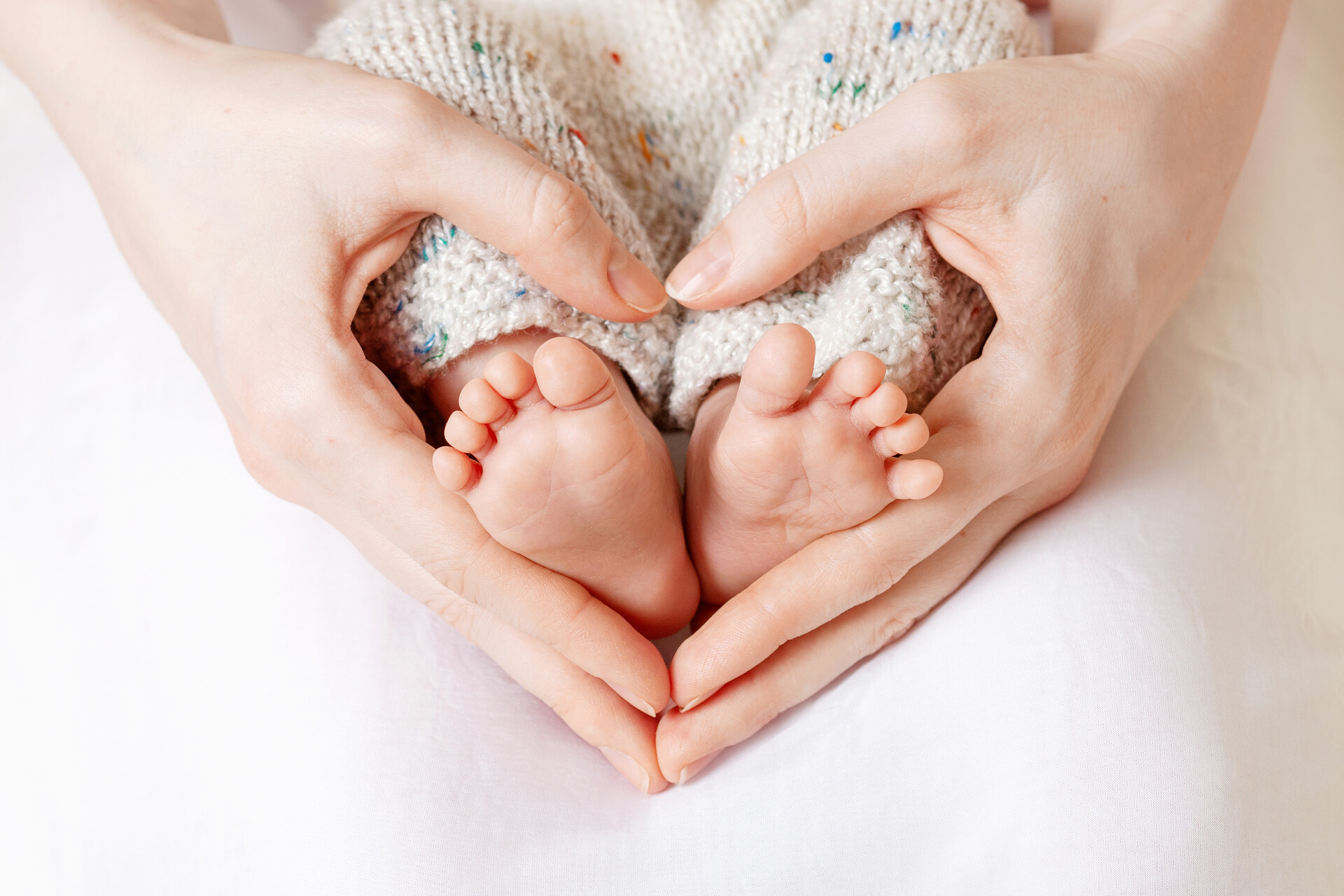baby feet mother hands tiny newborn baby s feet female heart shaped hands closeup